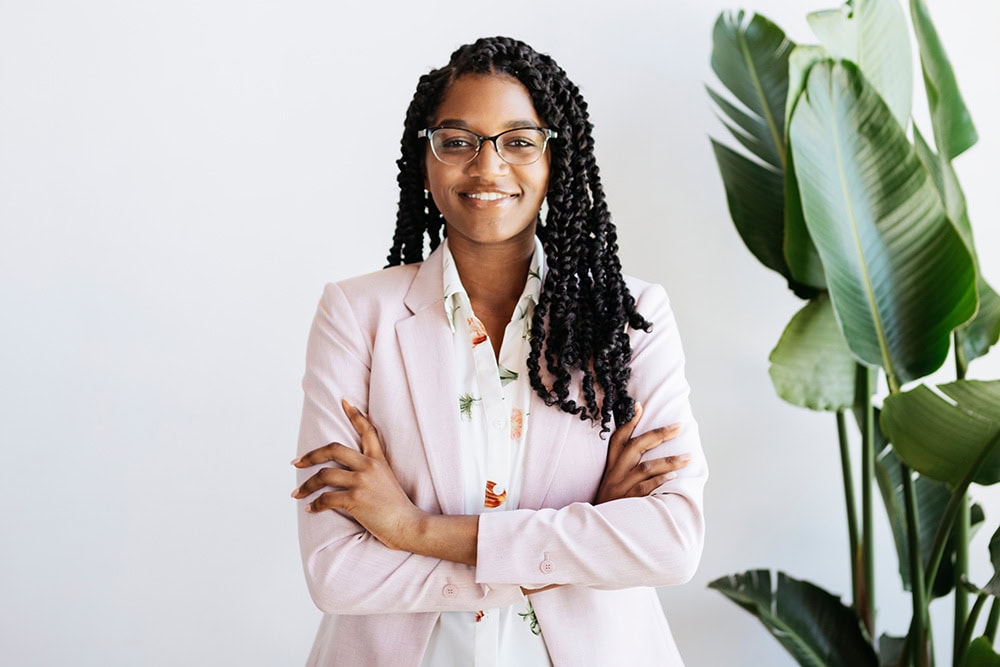 A woman stands smiling with her arms crossed