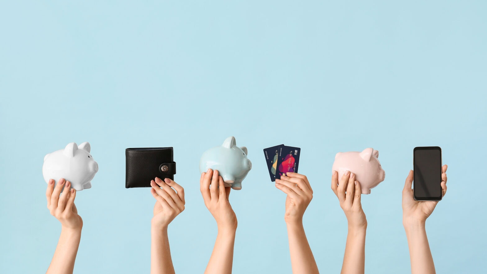 Female hands with piggy banks, credit cards, wallet and mobile phone on color background.