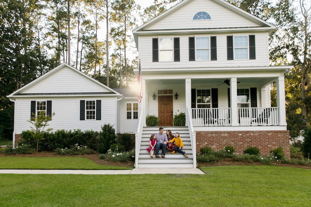 A family sits on the front steps of their home.