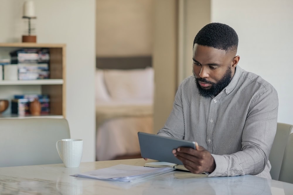 A man sits at his table and is working on his iPad