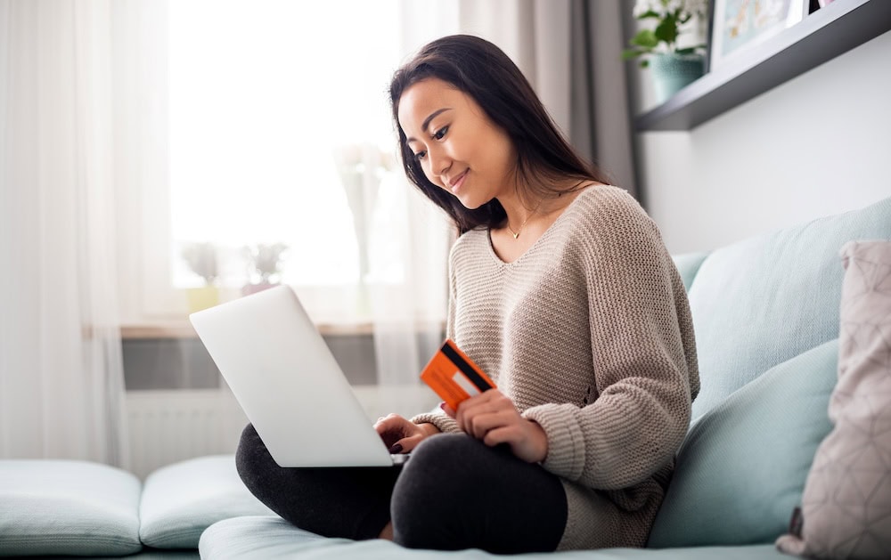 A woman sitting in front of her laptop and holding her credit card